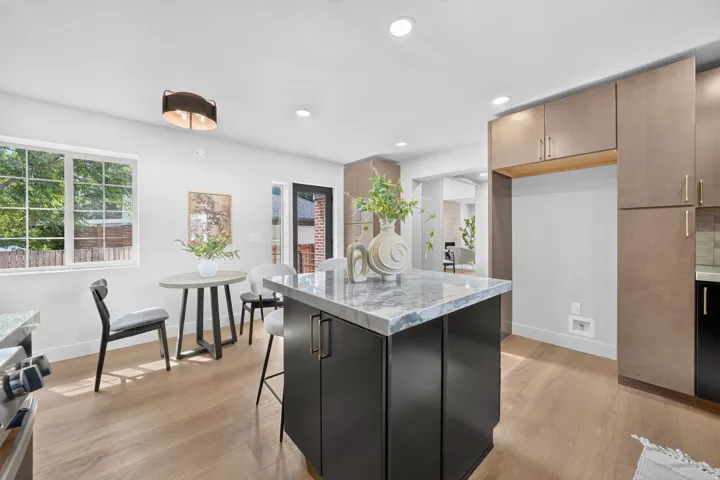 Kitchen featuring a central island with a stone countertop, light wood-finish flooring, recessed lighting, and ample cabinetry