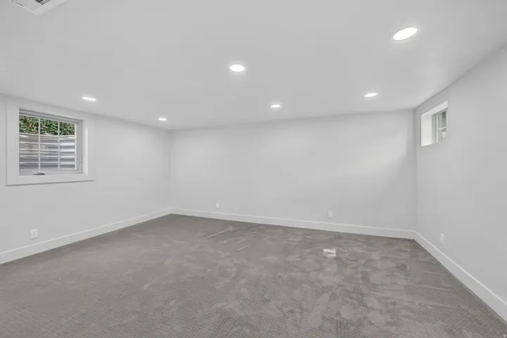 Spacious room with gray carpet flooring, white walls, recessed ceiling lighting, and two windows