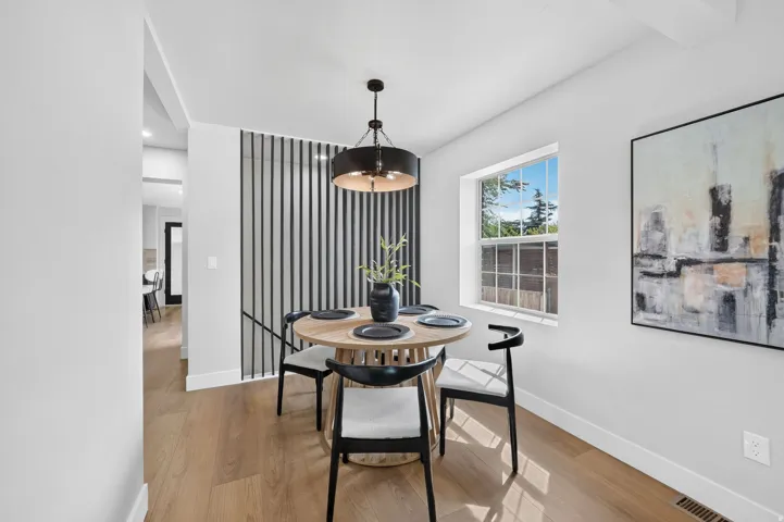 Wood-finish flooring, contemporary chandelier, large window, and decorative slatted wall feature