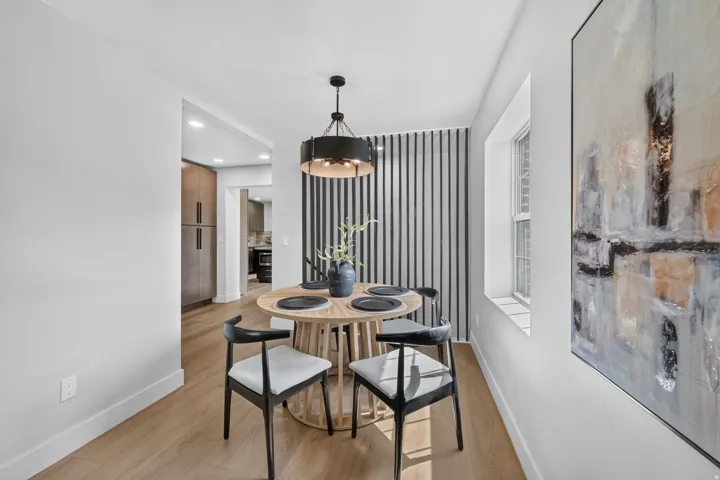Recessed window with deep sill, wood-finish flooring, accent wall with vertical slats, and a contemporary chandelier