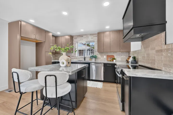 Kitchen featuring an island with stone countertop, stainless steel appliances, recessed lighting, and wood-finish flooring