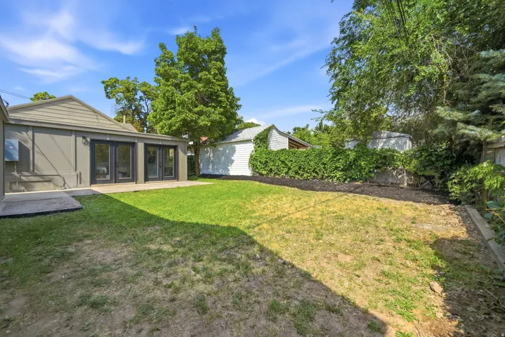Rear exterior with multiple French doors, concrete patio, and garden beds