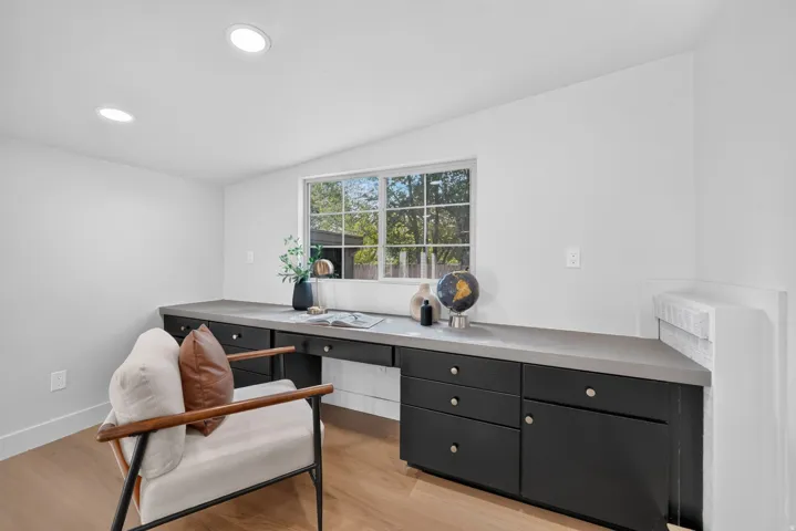 Built-in desk with dark cabinetry, light-toned countertop, and window with grid pattern