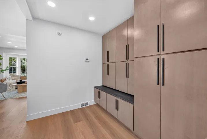 Built-in cabinetry with dark hardware, recessed lighting, and wood-finish flooring