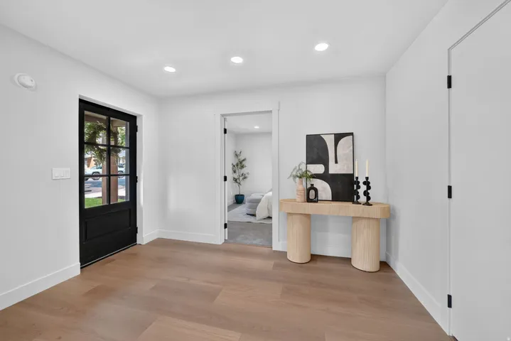 Light wood-finish flooring, recessed lighting, and a black paneled glass door