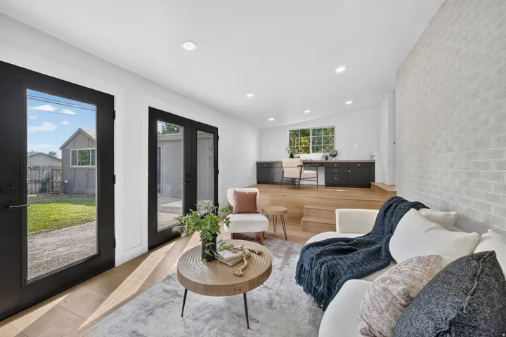 Bright, open-concept living space featuring recessed ceiling lighting, wide-plank wood-finish flooring, and abundant natural light from French doors and windows