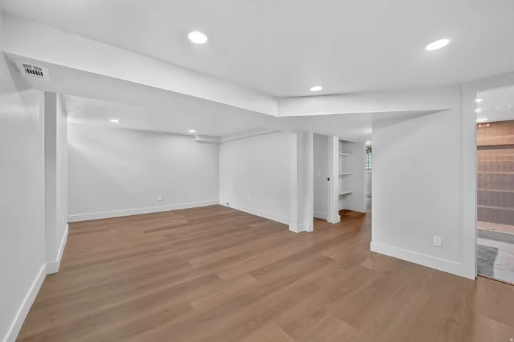 Recessed lighting illuminates the open area with wood-finish flooring