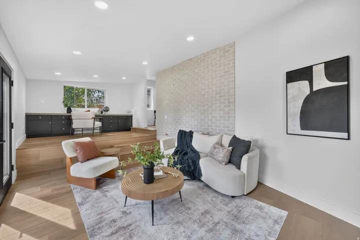 Recessed ceiling lighting, wood-finish flooring, accent brick wall, built-in cabinetry, and a large window