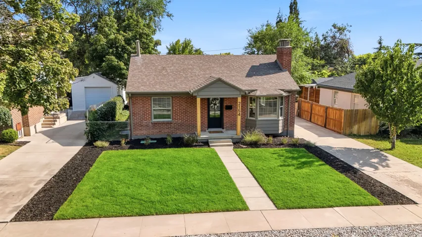 Brick-clad residence featuring a gabled roof, prominent front chimney, and a detached garage