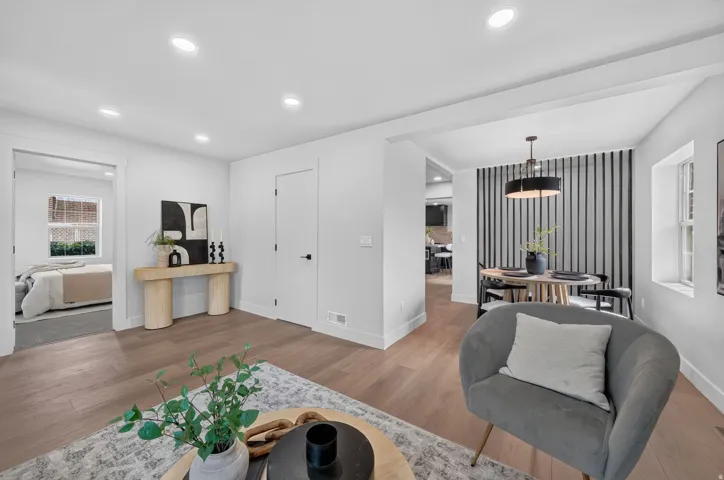 Recessed lighting, wood-finish flooring, white walls, and an open doorway leading to an additional room