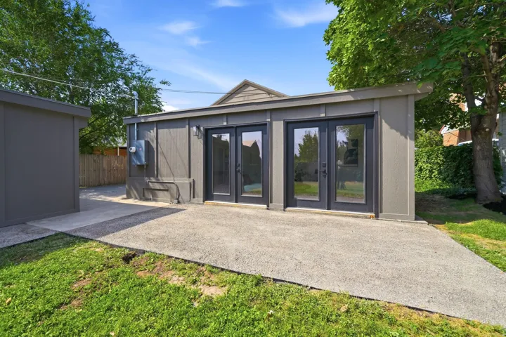 Modern outbuilding with two sets of double glass doors, a sloped roofline, and an exterior light fixture