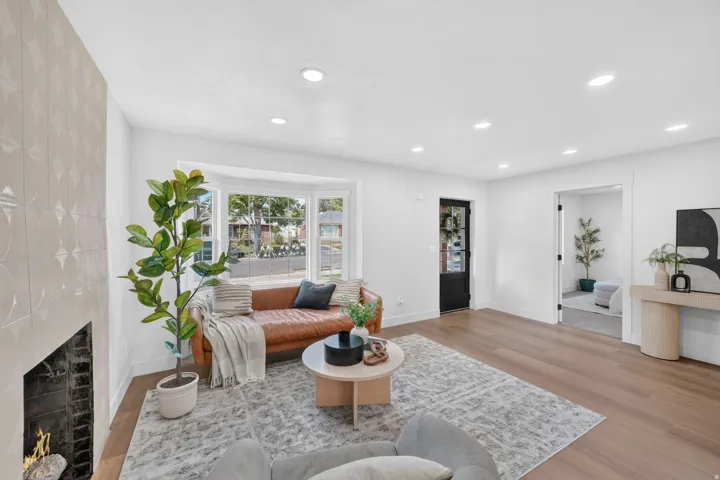 Recessed lighting, wood-finish flooring, fireplace with decorative surround, bay window, and a paneled entry door