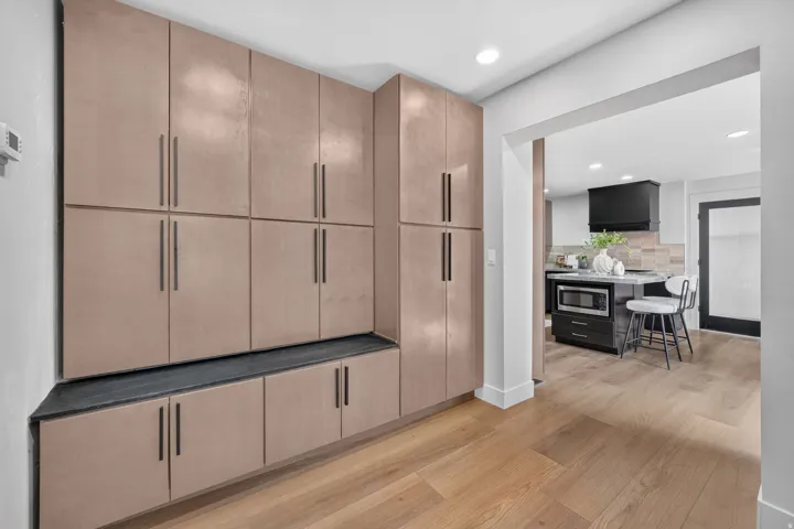 Built-in cabinetry with integrated seating, wood-finish flooring, recessed lighting, and an open entryway to the kitchen