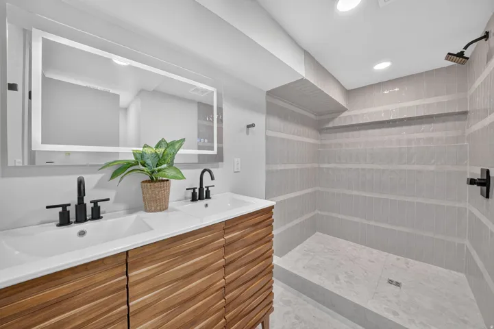 Dual vanity with integrated sinks, wood-finish cabinetry, and matte black fixtures