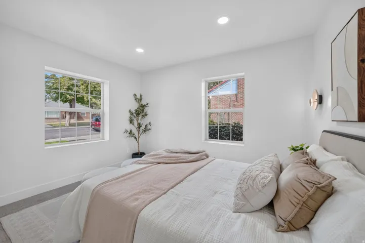 Recessed ceiling lighting, two double-hung windows, wall-mounted sconce lighting, and wood-finish flooring