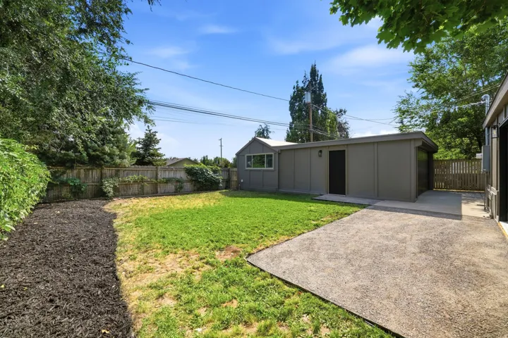 Expansive backyard featuring a gravel patio, manicured lawn, and privacy fencing