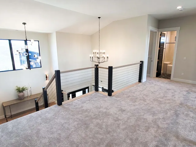 Carpeted loft area with cable railing and a vaulted ceiling