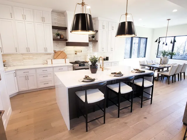 Open-concept kitchen with a large central island, white cabinetry, integrated range hood, and light wood-finish flooring