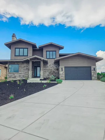 Contemporary exterior featuring stone veneer and horizontal siding, an integrated two-car garage, and a concrete driveway