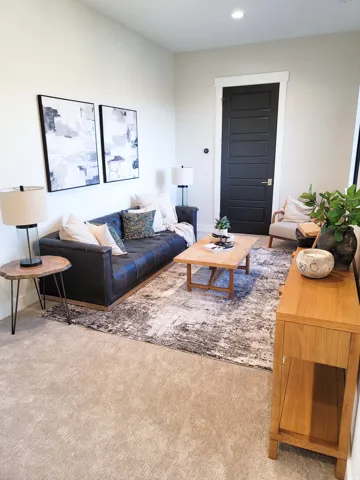Recessed ceiling lighting illuminates a room with light-colored walls and a neutral-toned carpet