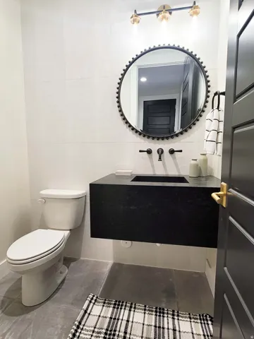 Floating vanity with an integrated basin, matte black wall-mounted faucet, and a decorative round mirror
