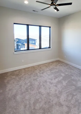 Recessed lighting, ceiling fan with integrated lighting, multiple pane window, wall-to-wall carpeting, and neutral wall tones