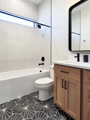 Bathtub with matte black fixtures, integrated showerhead, and white subway tile surround