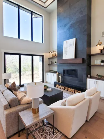 Two-story living area featuring a full-height stone-clad fireplace with a dark wood mantel and integrated firebox