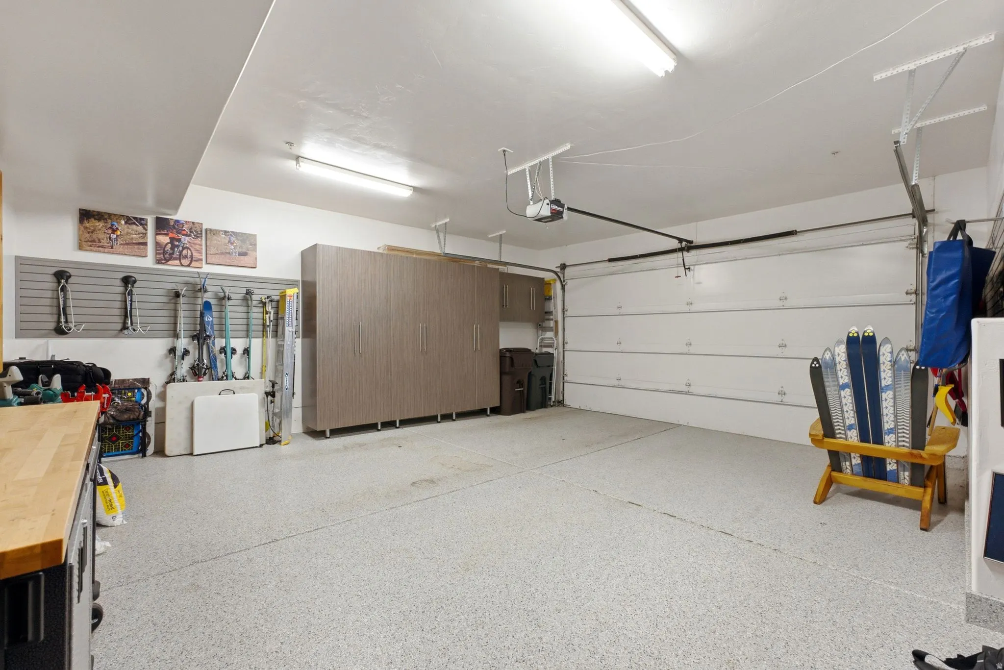 Epoxy-coated garage flooring with integrated storage cabinets, wall-mounted organization system, and overhead lighting