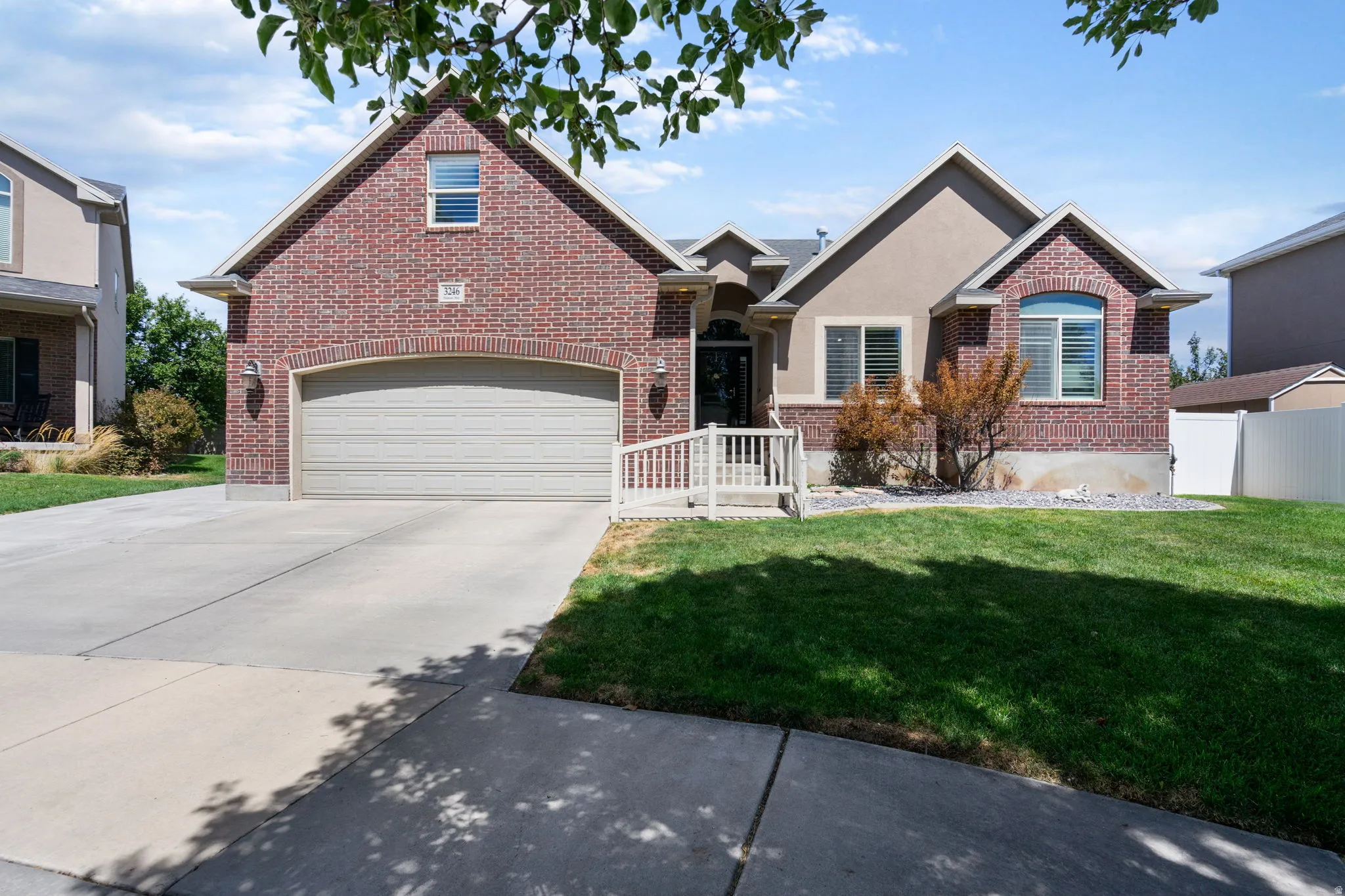 Brick and stucco exterior with an arched garage door, white railing, and an arched window