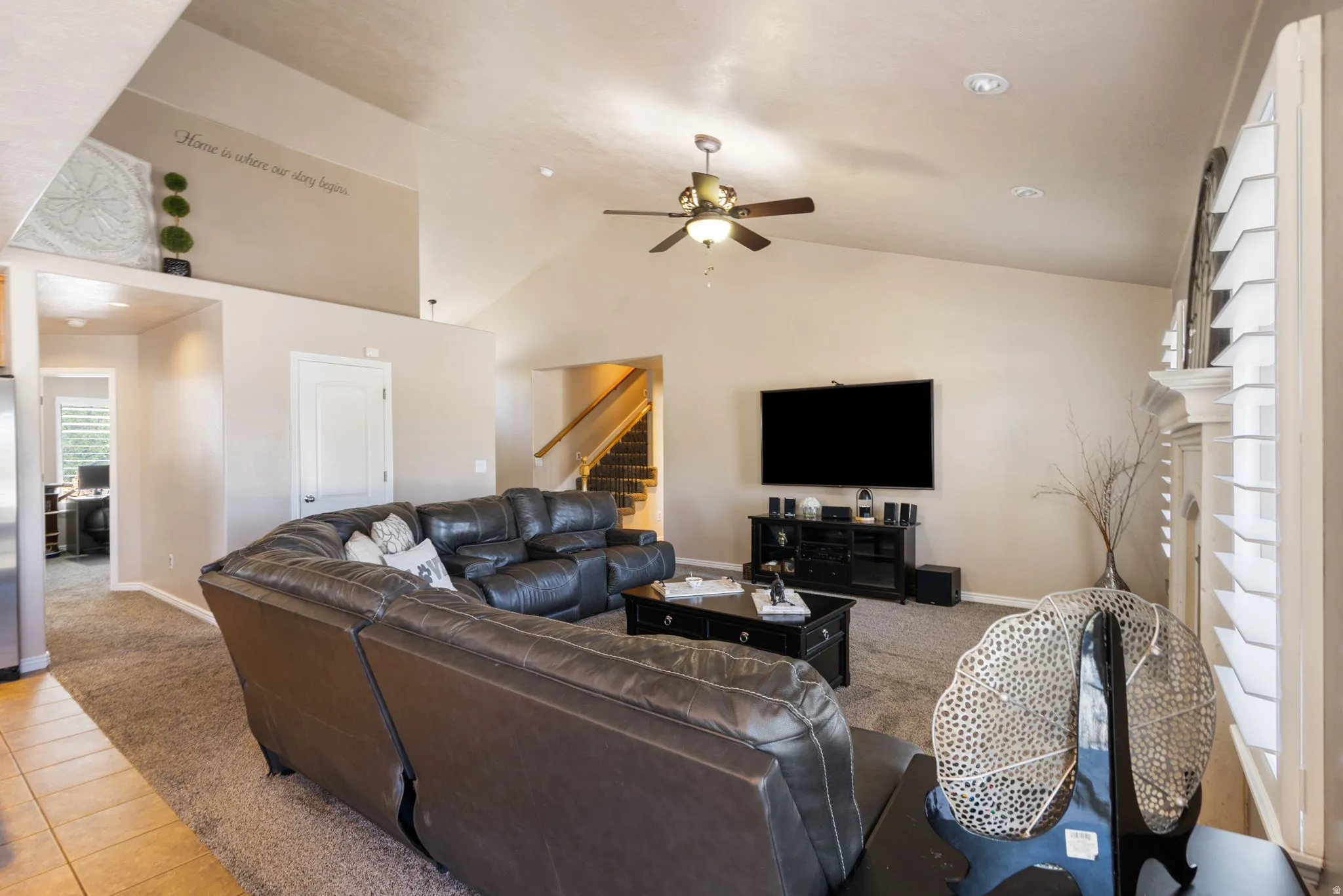 Vaulted ceiling with recessed lighting, ceiling fan, carpet flooring, and a staircase with wood railings