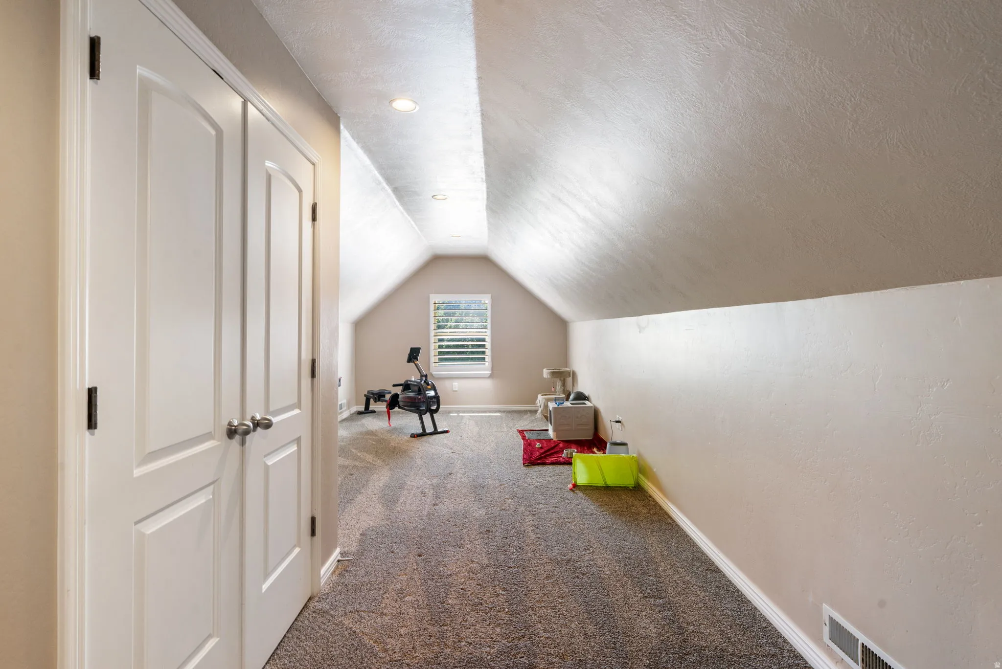 Carpeted area with a window, recessed lighting, and white bi-fold doors