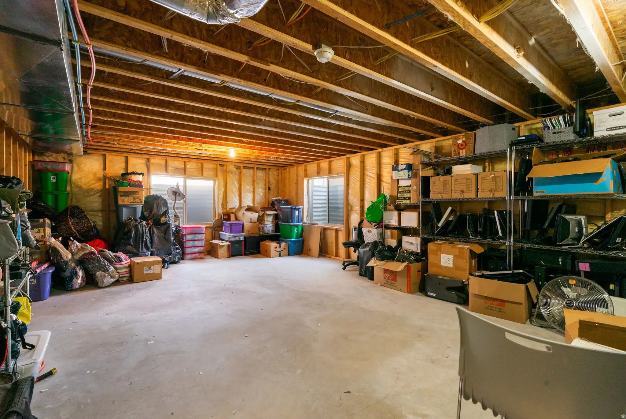 Unfinished basement featuring exposed wood joists, concrete flooring, and multiple window openings