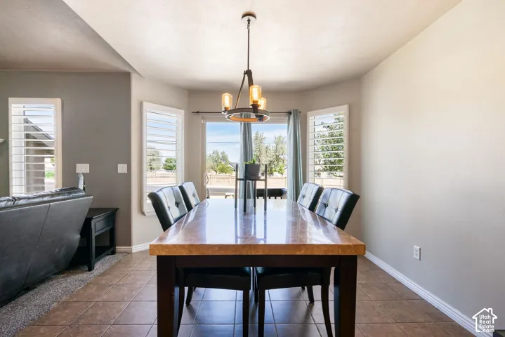 Bay window with window shutters, tile flooring, and a contemporary chandelier
