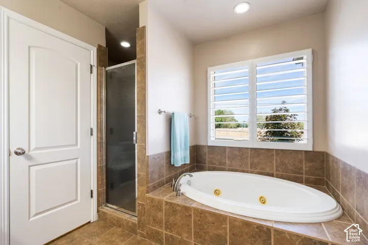 Built-in soaking tub with gold-tone fixtures, tiled surround, and plantation shutters