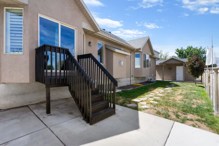 Private backyard with a concrete patio, wooden privacy fence, and stone pathway
