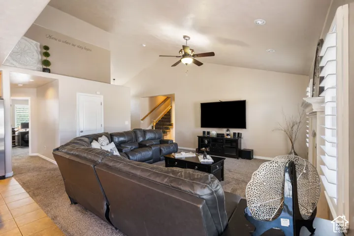 Vaulted ceiling with recessed lighting, ceiling fan, carpet flooring, and a staircase with wood railings