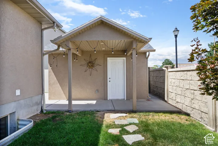 Covered patio with concrete flooring, stucco exterior, and a privacy wall