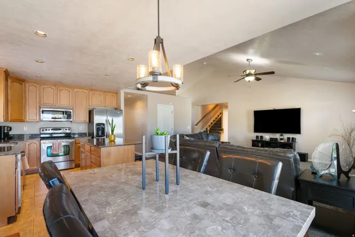 Open-concept living area featuring a vaulted ceiling with a ceiling fan, recessed lighting, and a chandelier