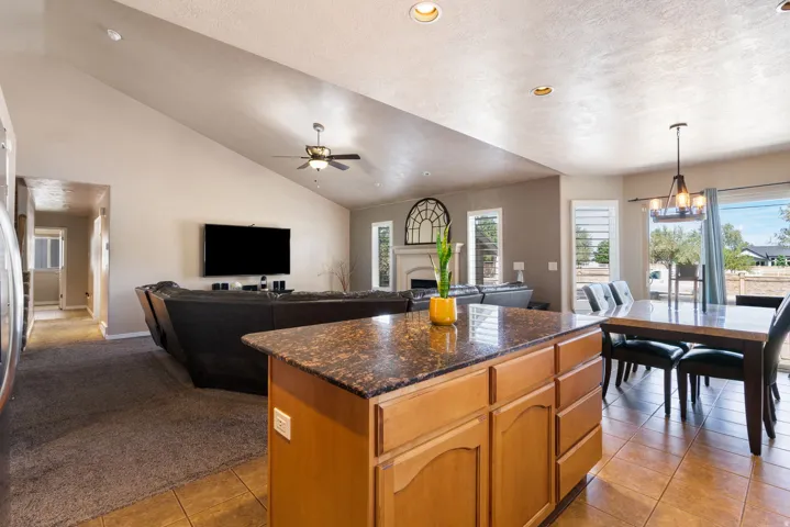 Open-concept living area featuring a vaulted ceiling with a ceiling fan, recessed lighting, and tile flooring