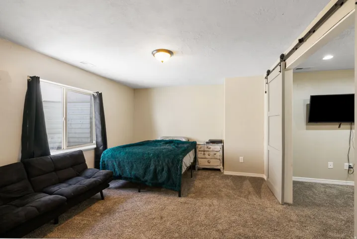 Carpeted flooring, recessed window, ceiling-mounted light fixture, and a sliding barn door with black hardware