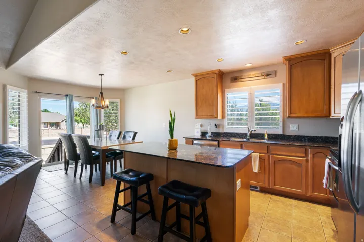 Kitchen featuring wood cabinetry, dark countertops, a stainless steel refrigerator, and recessed lighting