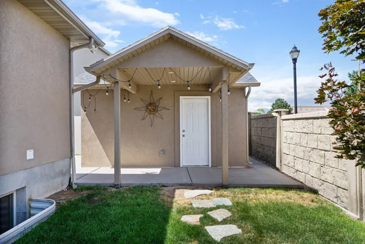 Covered patio with concrete flooring, stucco exterior, and a privacy wall