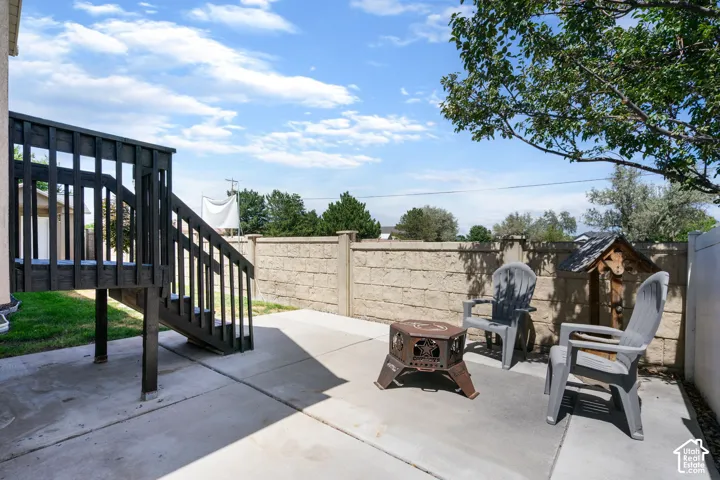 Concrete patio with a dark wood deck and stairs, complemented by a block retaining wall