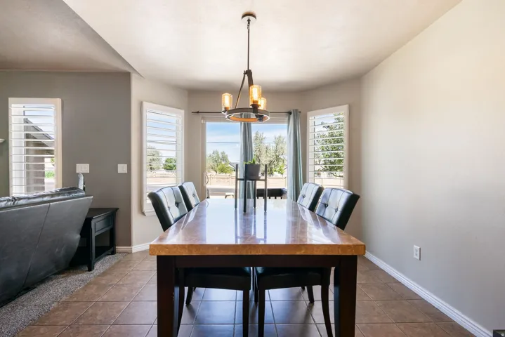 Bay window with window shutters, tile flooring, and a contemporary chandelier