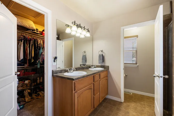 Dual vanity with integrated sinks, wood-finish cabinetry, and a large wall-mounted mirror