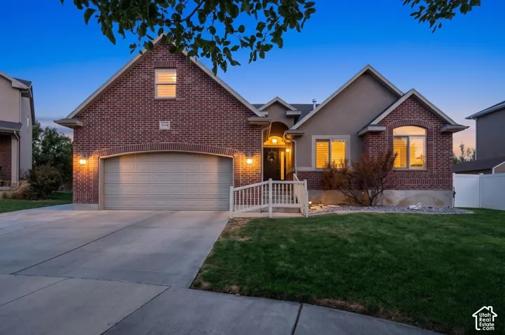 Brick and stucco exterior with an arched garage door, concrete driveway, and front lawn