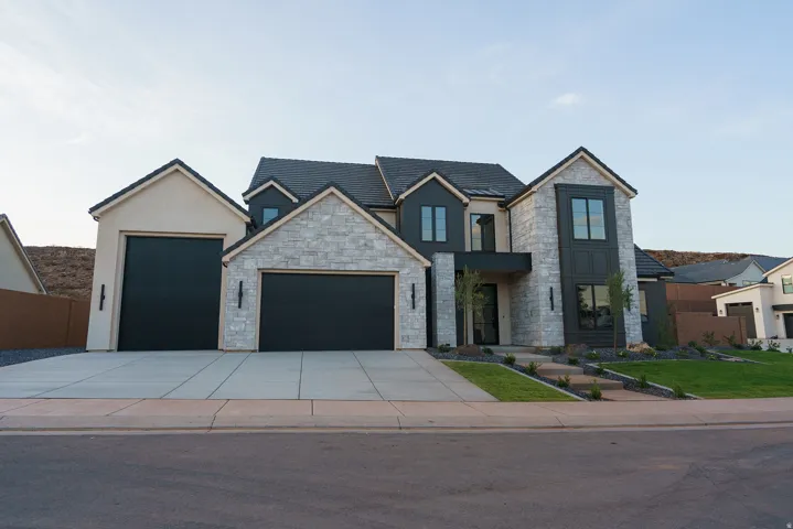 Contemporary home featuring a stone and stucco exterior, black garage doors, dark framed windows, and a multi-level concrete driveway