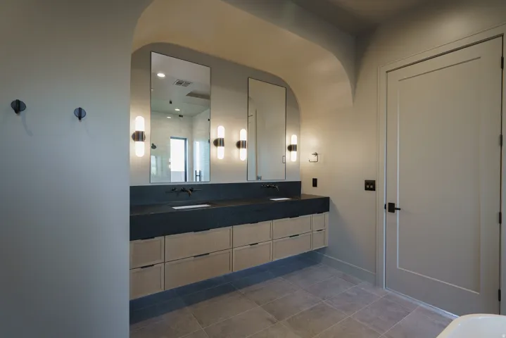 Floating dual vanity with integrated sinks, wood-finish cabinetry, and matte black fixtures