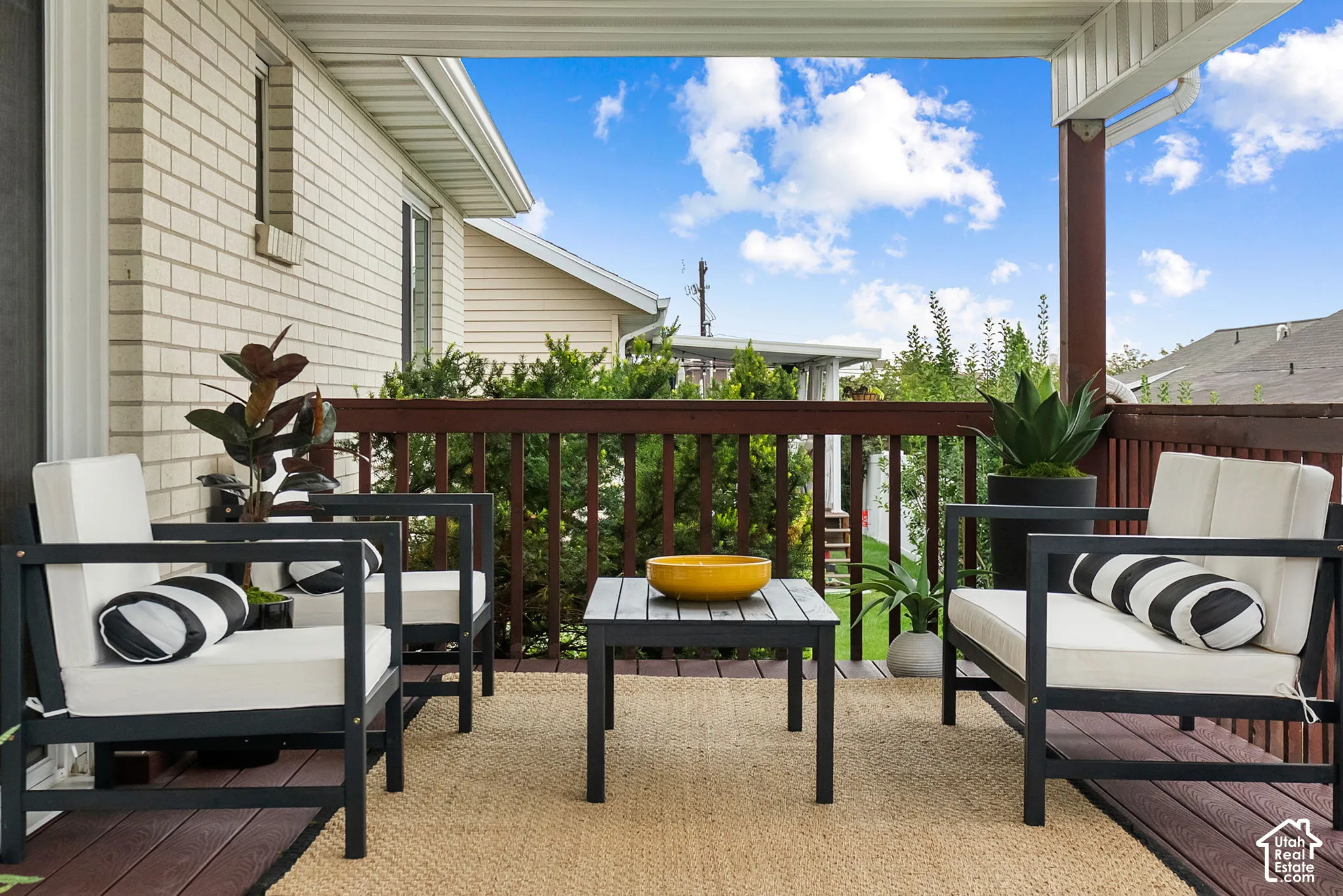 Covered outdoor deck with a dark wood-finish floor and a light-colored woven rug